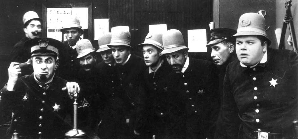 A scene from 'In the Clutches of the Gang', a Keystone Cops silent comedy directed by George Nichols and Mack Sennett. Left to right : Ford Sterling (on phone), Edgar Kennedy, George Jeskey, Al St John, Hank Mann, Rube Miller, and Roscoe Fatty Arbuckle (1887 - 1933).   (Photo by Hulton Archive/Getty Images)